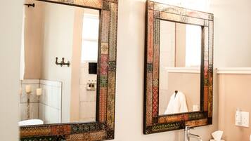 A bathroom with two white sinks, a large mirror with a decorative frame, and a towel rack with folded towels.