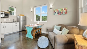A compact kitchen with a wooden ceiling, a large window, and a dining area with a bench. - Hill Country Casitas (Dripping Springs)