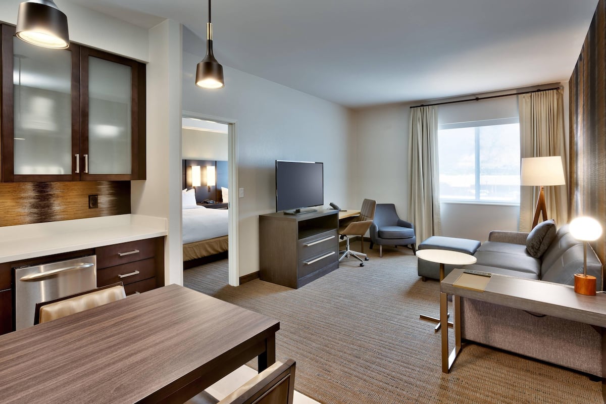 Ein Hotelzimmer mit einer Küchenzeile, einem Bett, einem Schreibtisch, einer Couch und einem Fernseher.