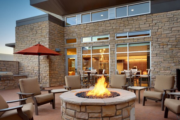 An outdoor patio with stone walls, a fire pit, and outdoor seating.