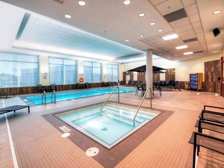 Zona de piscina con sillones de descanso, vestuarios y mostrador de recepción.