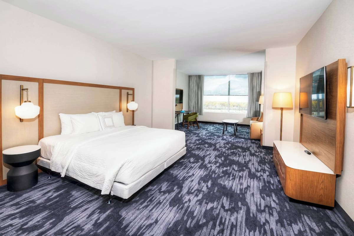 Een hotelkamer met een groot bed, een bureau, een stoel en een raam met uitzicht.