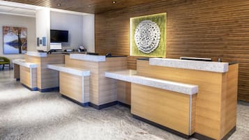 A reception area with wooden reception desks, a flat-screen TV, and a decorative wall piece.