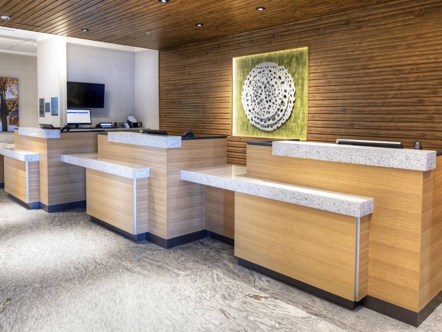 A reception area with wooden reception desks, a flat-screen TV, and a decorative wall piece.