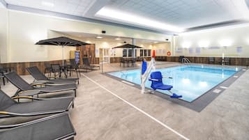 A swimming pool area with lounge chairs, a changing room, and safety signage.