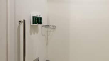 A modern bathroom with a walk-in shower, a grab bar, a handheld showerhead, and a white bathtub.