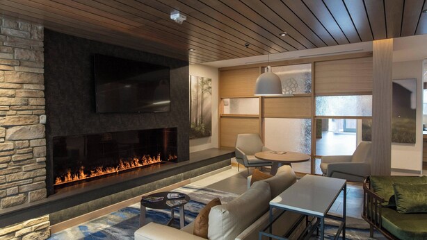 A modern living room with a stone fireplace, a flat-screen TV, and comfortable seating.