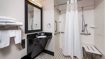 A modern bathroom with a black sink, white tiles, a glass shower enclosure, and a white shower curtain.