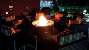 An outdoor seating area with wicker furniture and a central fire feature.