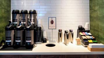 A coffee station with multiple coffee dispensers, a coffee machine, and a variety of coffee cups and mugs.