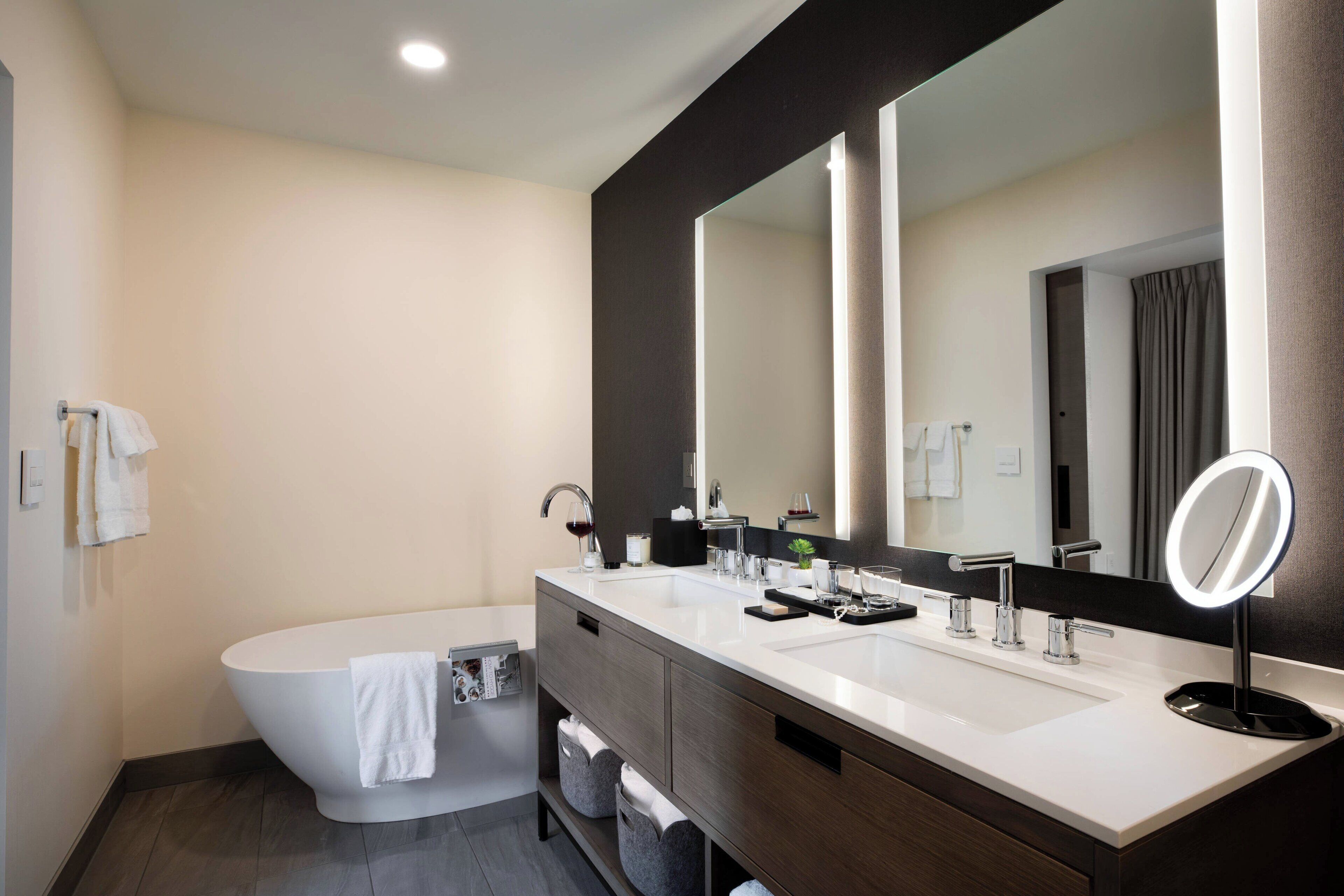 Une salle de bain moderne avec une baignoire sur pieds, un meuble-lavabo à deux vasques et un grand miroir.