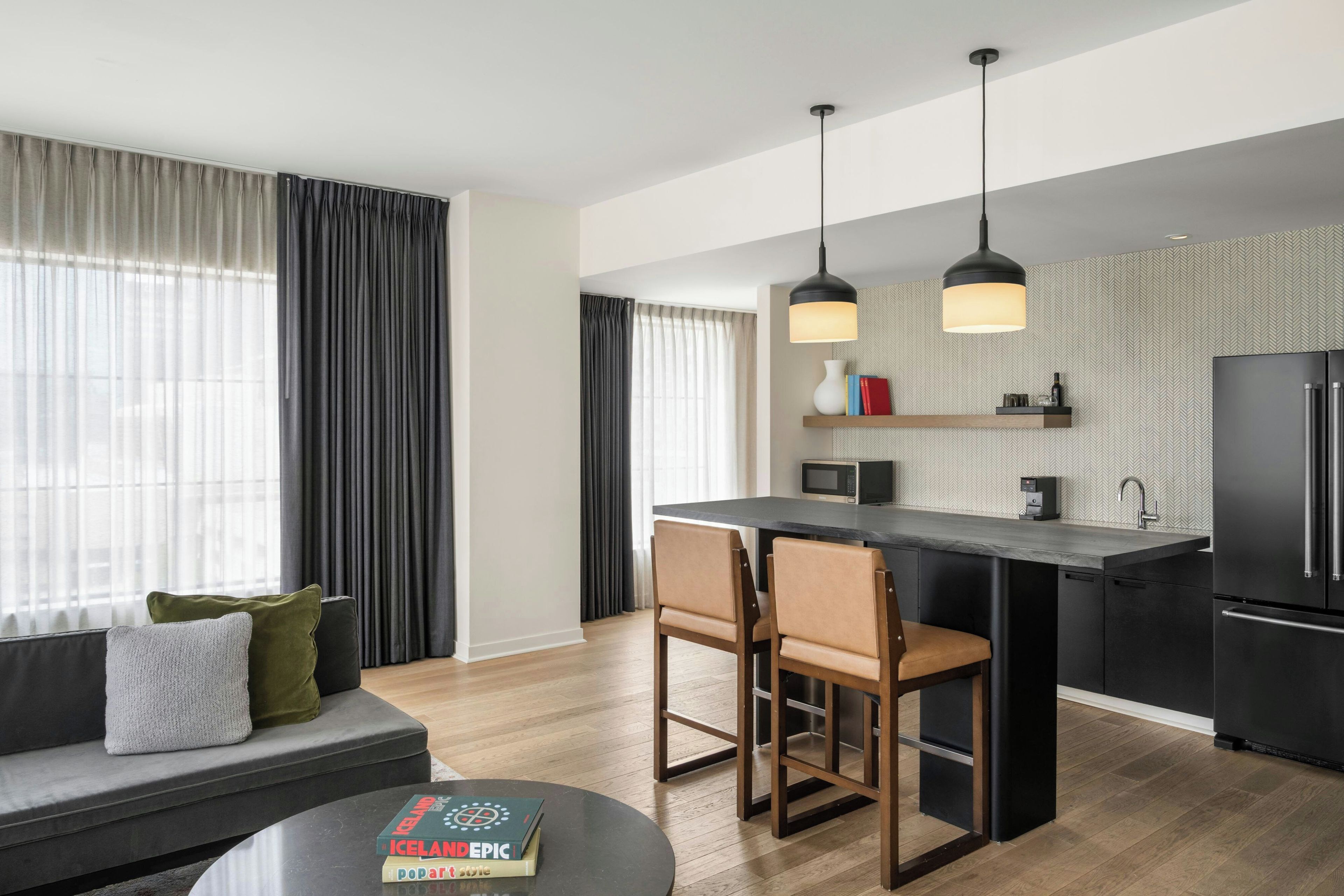 Una cocina moderna con una isla central, electrodomésticos negros e iluminación colgante.