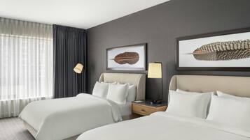 A hotel room with two beds, a nightstand, a lamp, and two framed pictures on the wall.