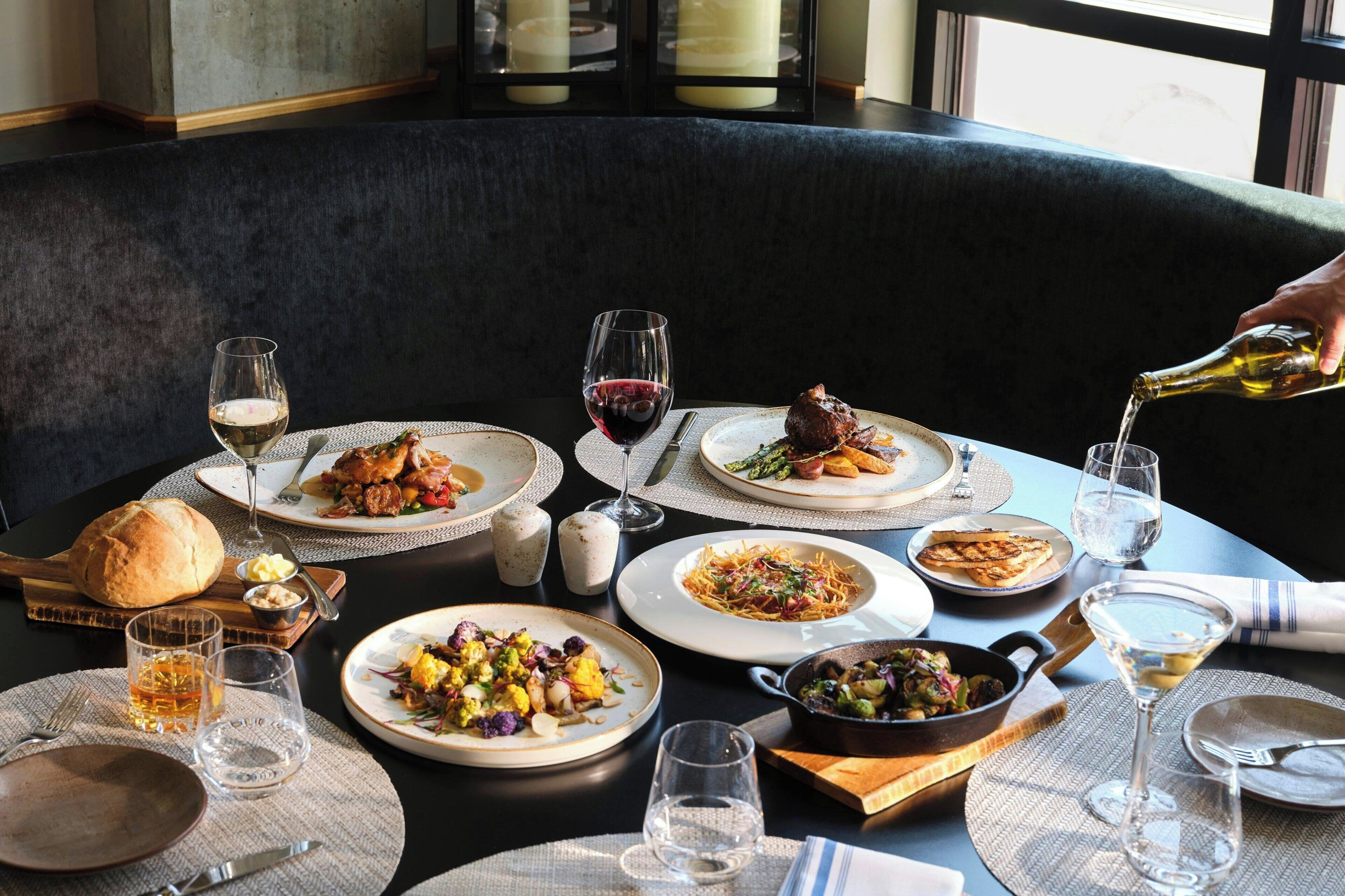 A dining table set with various dishes, glasses, and a bottle of wine, suggesting a meal setting.