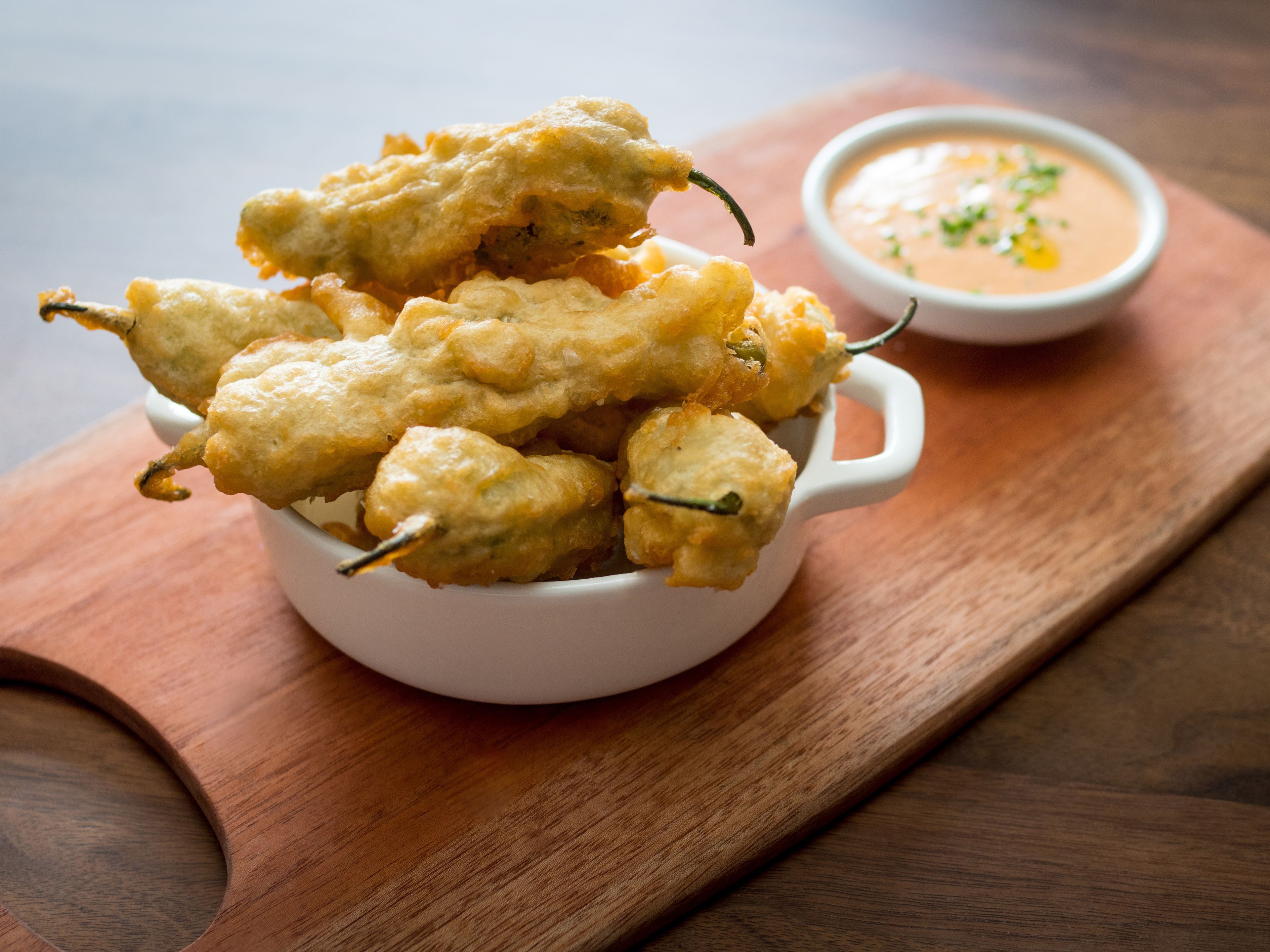 A white bowl filled with fried food items on a wooden board.