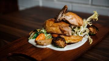 Una mesa de madera con un pollo asado, verduras y salsa cremosa.