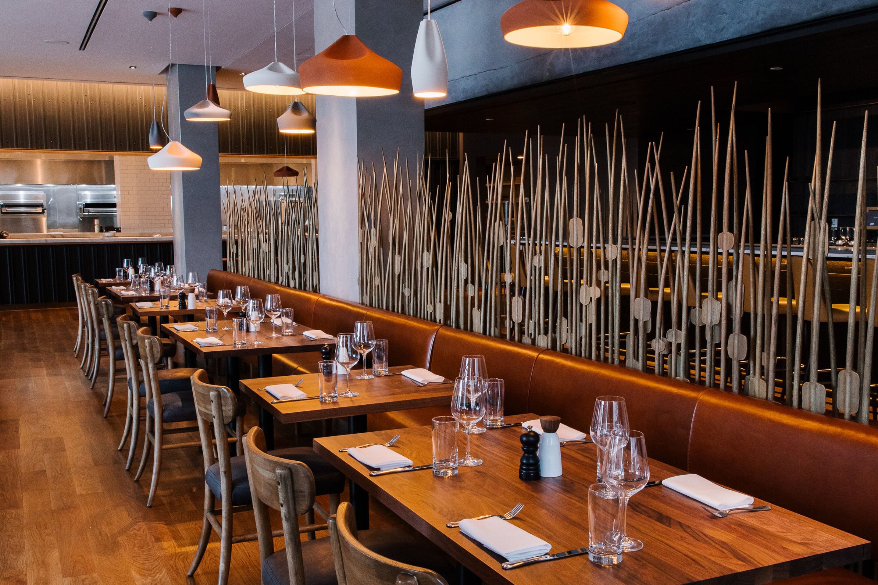 Un restaurante con mesas y sillas de madera, y lámparas colgantes.
