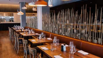 Un restaurante con mesas y sillas de madera, y lámparas colgantes.