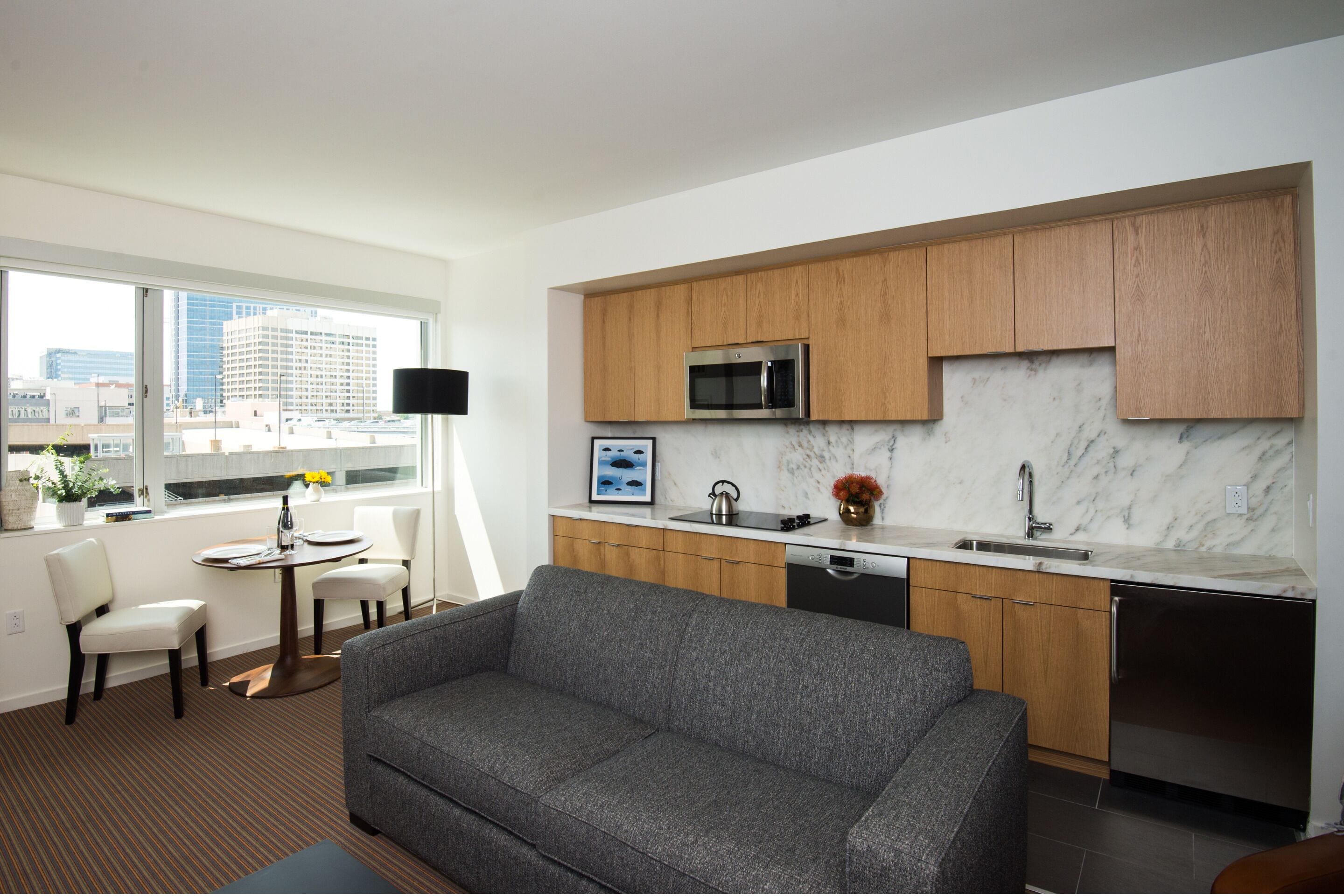 A modern kitchen with wooden cabinets, a built-in microwave, and a marble countertop.