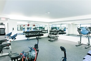 Un gimnasio con equipo cardiovascular, máquinas de pesas y mancuernas.