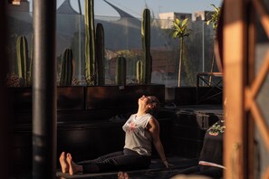 Una persona seduta su una panchina all'aperto, con cactus e piccole piante sullo sfondo.