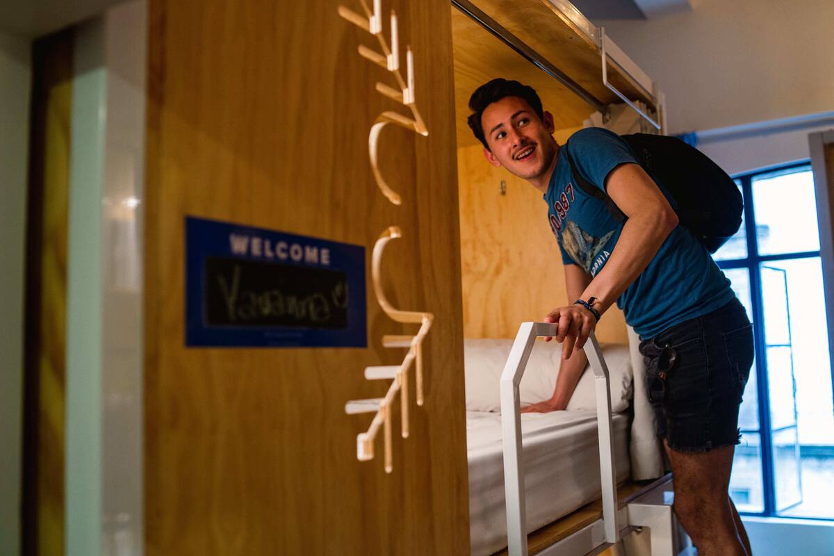 A person leaning on a bed in a room with a 'Welcome' sign.