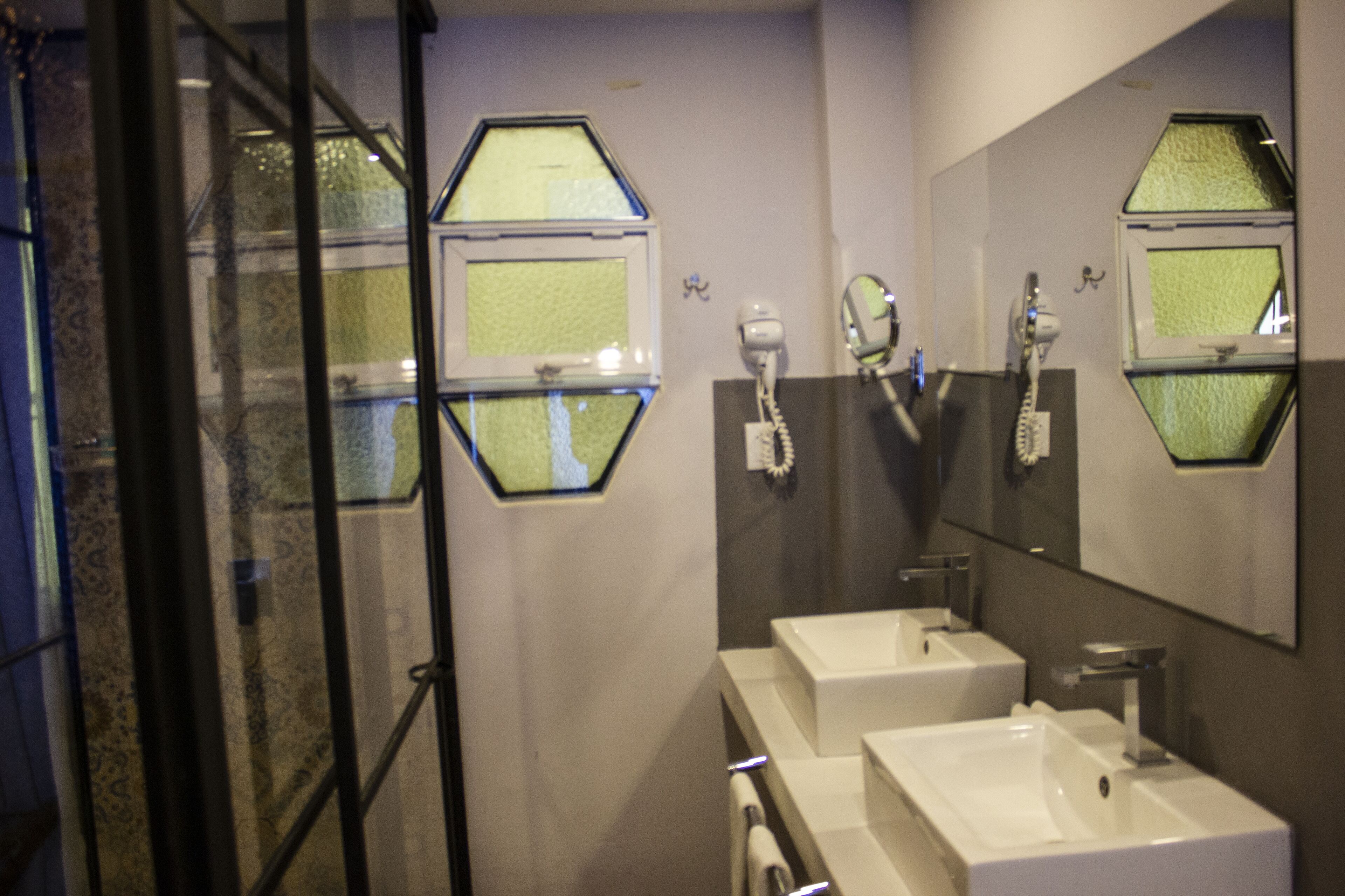 A bathroom with two sinks, a mirror, and a hairdryer.