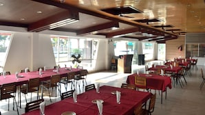 A spacious dining area with multiple tables and chairs, large windows, and a modern ceiling design. - Inani Royal Resort (Cox's Bazar)