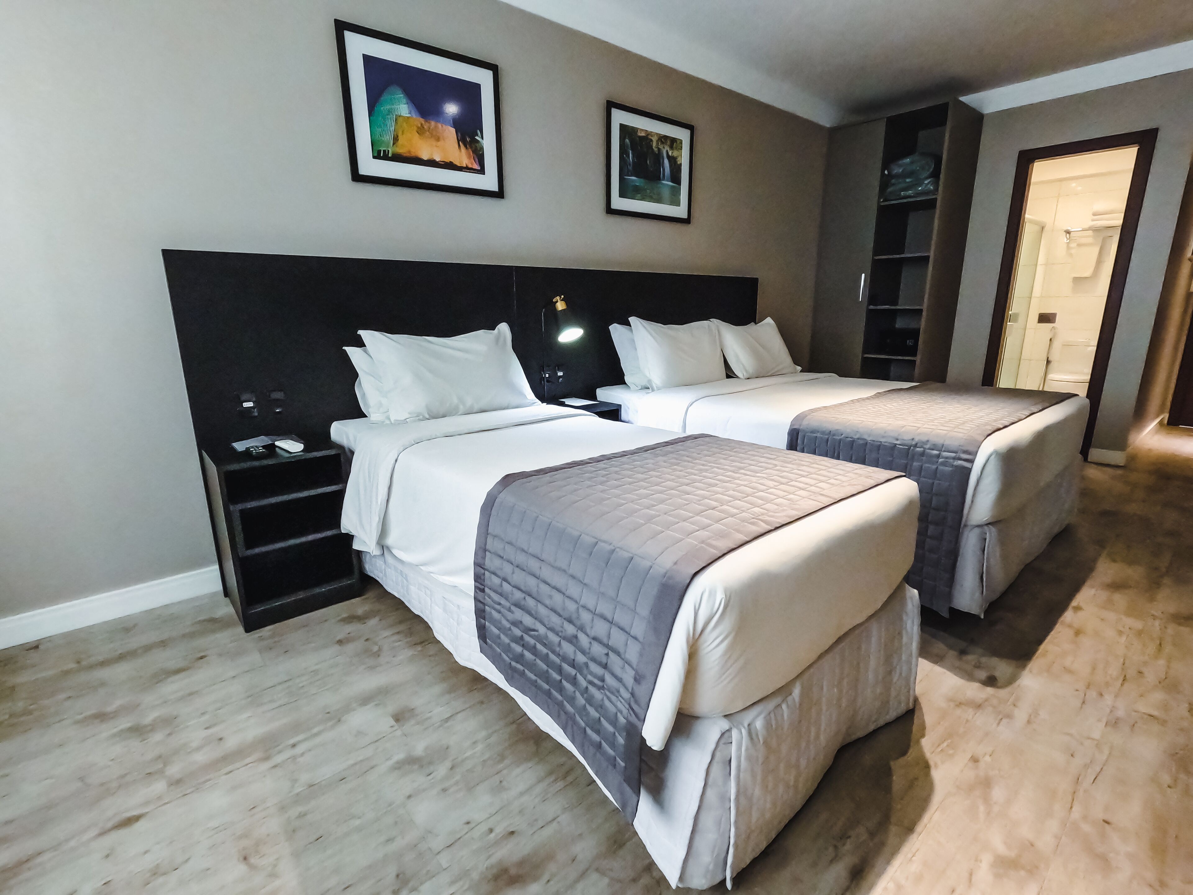 A hotel room with two beds, a nightstand, a desk, and a bookshelf.