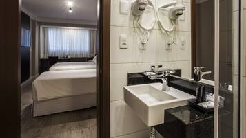 Ein Hotelzimmer mit Bett, Badezimmer mit Waschbecken und Spiegel.