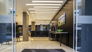 A modern hotel lobby with a reception desk, a digital display, and a reception area. - Santa Inn Hotel (Balneário Camboriú)