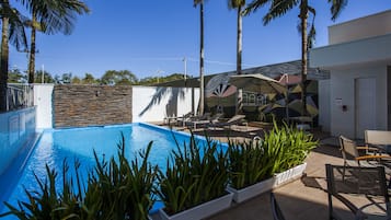 Una piscina al aire libre, sillones reclinables de piscina