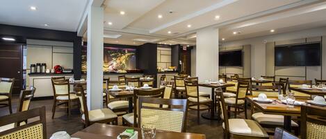 A restaurant with multiple dining tables and chairs, a buffet area, and a kitchen in the background.
