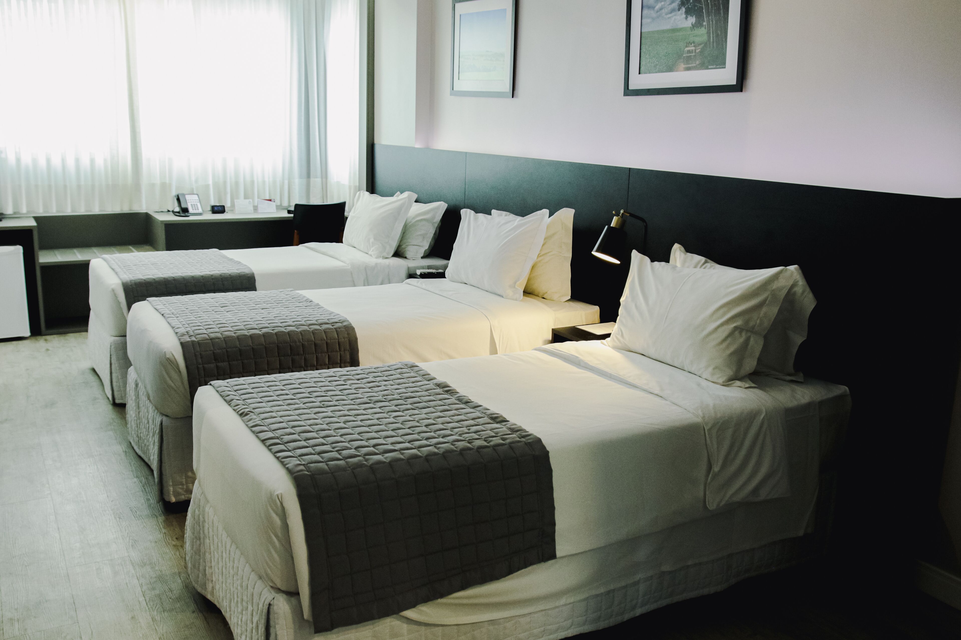 A hotel room with two beds, a desk, a chair, and a nightstand.