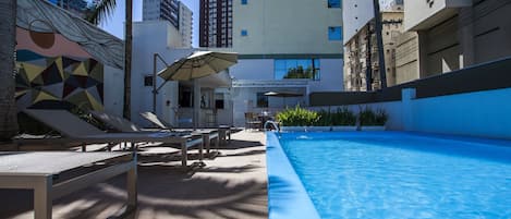Una piscina al aire libre, sillones reclinables de piscina