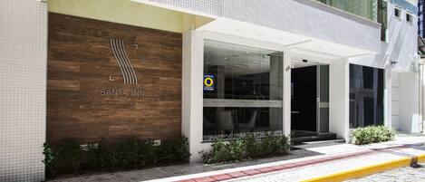 A modern Santa Inn hotel with a large wooden facade, glass entrance, and a yellow curb.