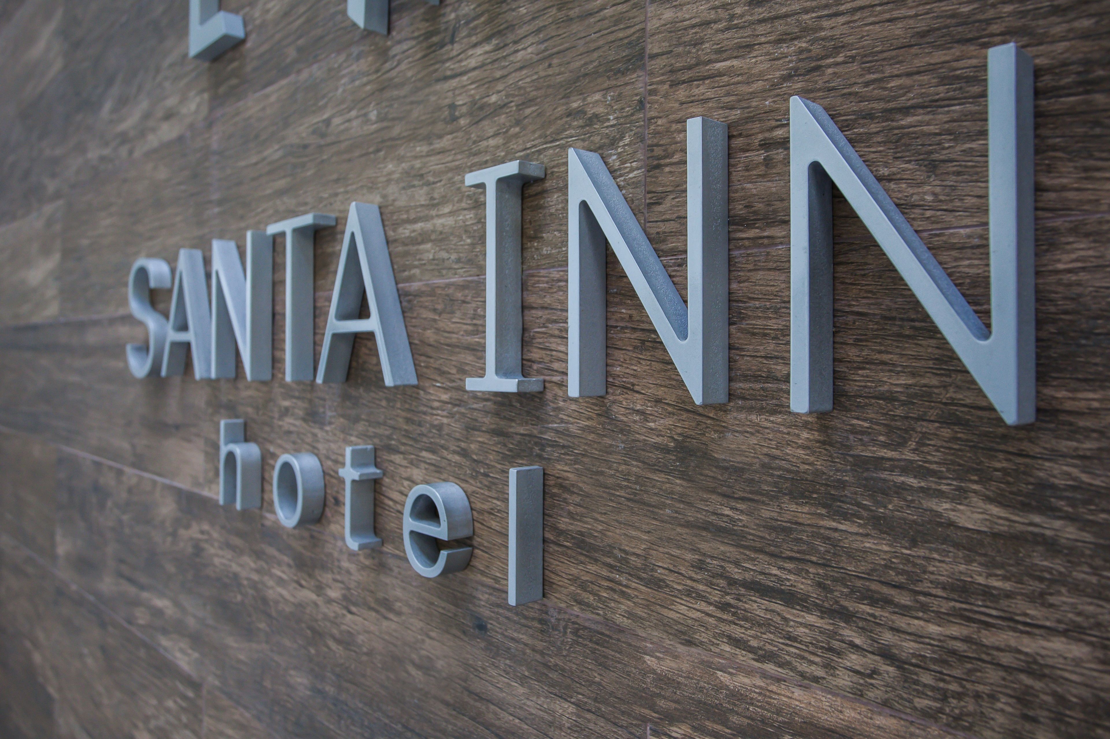 Un mur en bois sur lequel on peut lire, en lettres métalliques, l’inscription « SANTA INN Hotel ».