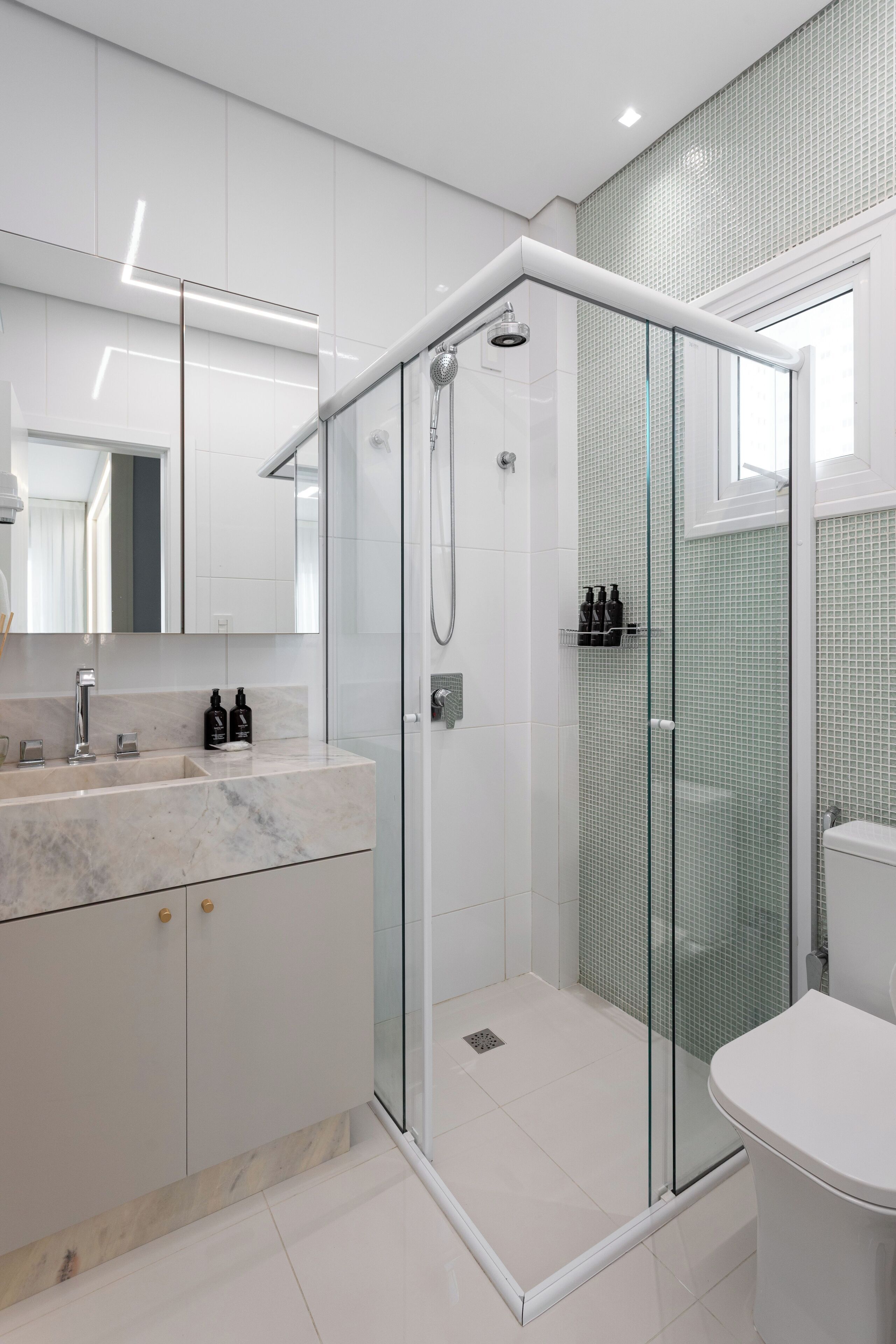 Un baño moderno con ducha de vidrio, lavamanos de mármol y un inodoro.