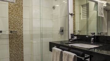 Une salle de bain moderne avec une douche à parois de verre, un lavabo sur un plan de toilette noir et un grand miroir.