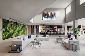 Amplia sala de estar con un sofá modular grande, dos mesas de centro y una pared verde con plantas.