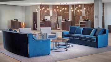 A modern lobby with a blue sofa, armchairs, and a reception desk.