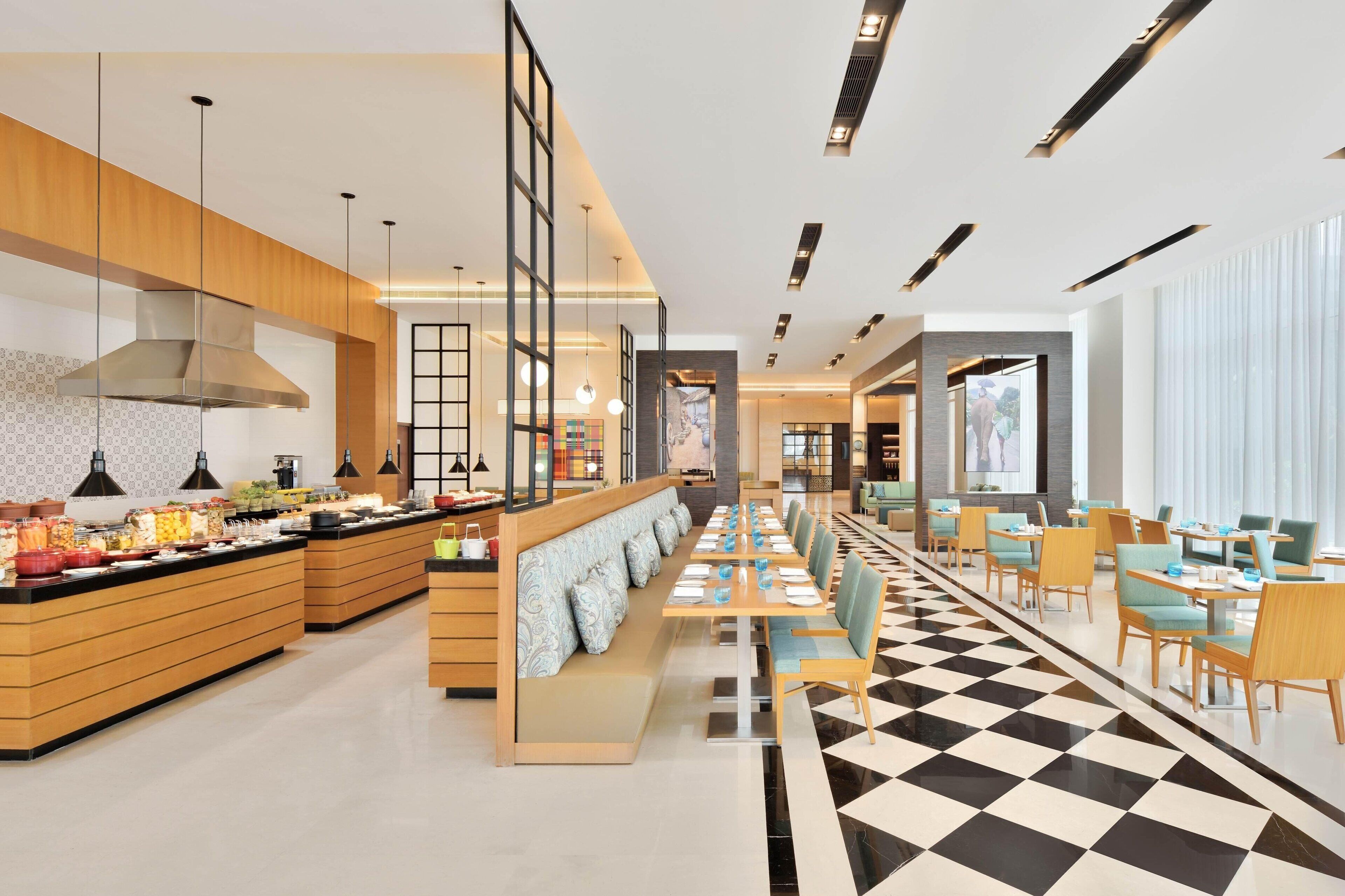 A modern hotel lobby with a buffet, seating area, and a check-in desk.