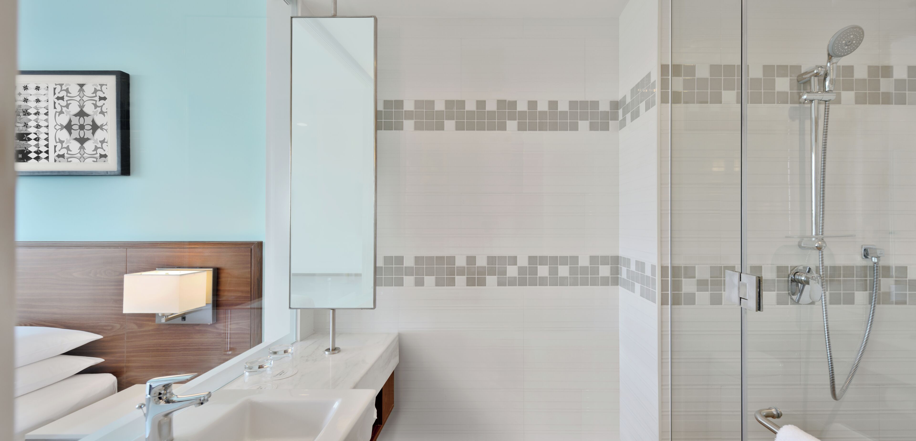 A modern bathroom with a glass-enclosed shower, a large mirror, and a wall-mounted light fixture.
