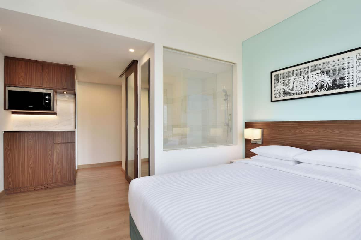 Une chambre d’hôtel comprenant un lit, une télévision, une armoire en bois, un miroir et un tableau accroché au mur.