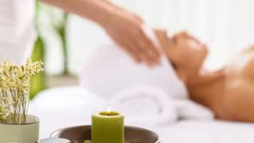 Een wellness omgeving met een persoon die een massage krijgt, een kaars en een schaal met kruiden.