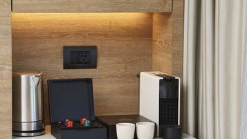 A modern kitchen with a built-in coffee machine, a kettle, and a box containing two mugs and a small decorative item.