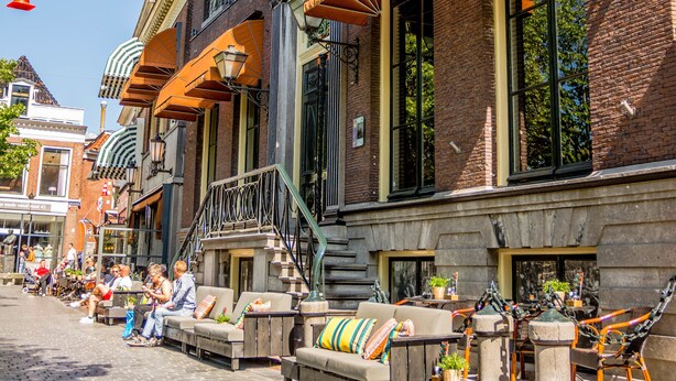 A brick building with outdoor seating and orange awnings. - Boutique Hotel Catshuis (Leeuwarden)