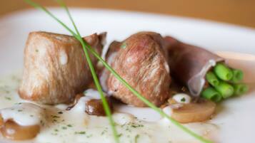 A plate of food with a creamy sauce, green onions, and a piece of meat.
