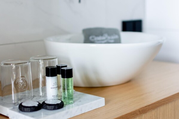 Un lavamanos de baño con encimera de mármol blanco, un lavabo blanco y un jabonera.