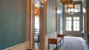 A hallway with a bench, a door, and a patterned rug. - Boutique Hotel Catshuis (Leeuwarden)